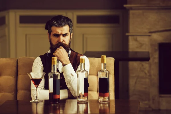 Mężczyzna siedzący przy stole z trzech butelek i szklanych — Zdjęcie stockowe