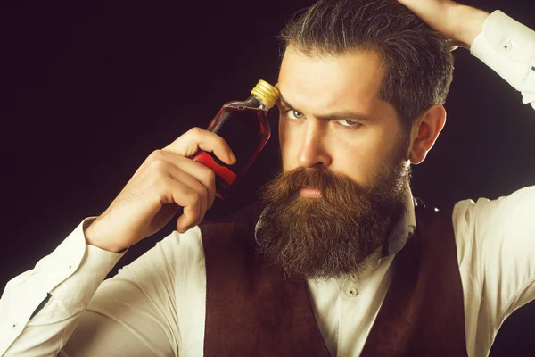 Homem segurando garrafa de licor vermelho no rosto franzido — Fotografia de Stock