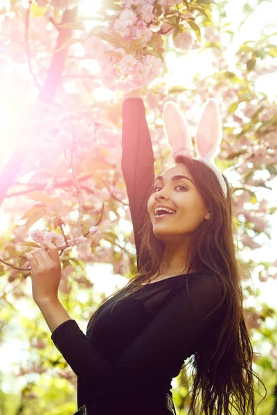 Meisje glimlachend met schattige bunny oren bij sakura tree — Stockfoto