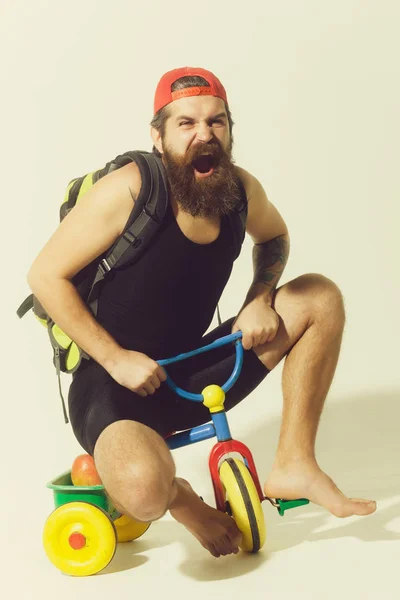 Barbudo gritando homem com saco, maçã na bicicleta brinquedo — Fotografia de Stock
