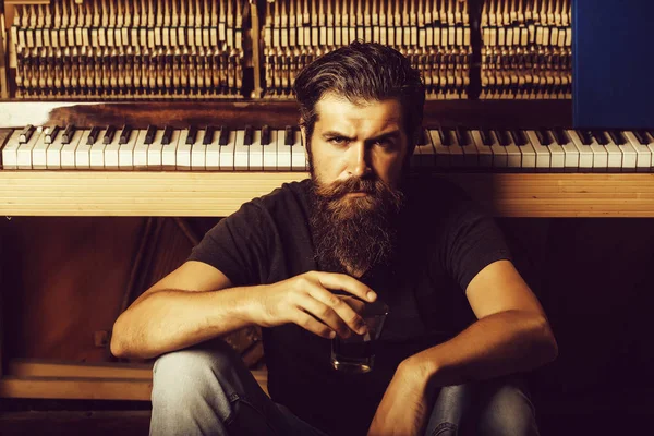 Homme barbu avec verre près du piano en bois — Photo