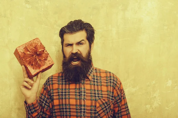 Кричащий бородатый мужчина с красной коробкой подарков с луком — стоковое фото
