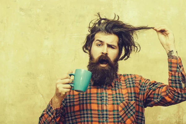 Sorprendido barbudo hombre tirando elegante flequillo cabello con azul taza —  Fotos de Stock