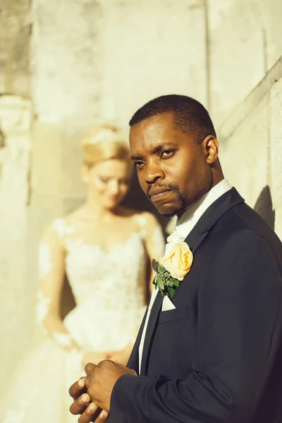 Handsome bearded african American groom touches wedding ring on