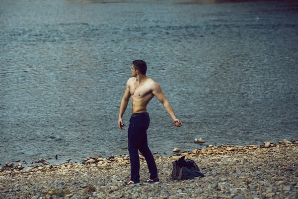 Homem muscular com saco perto de água — Fotografia de Stock