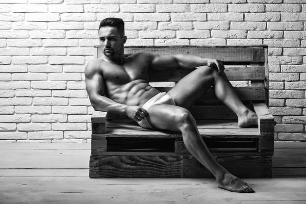 Pohledný svalnatý muž na dřevěné lavici — Stock fotografie