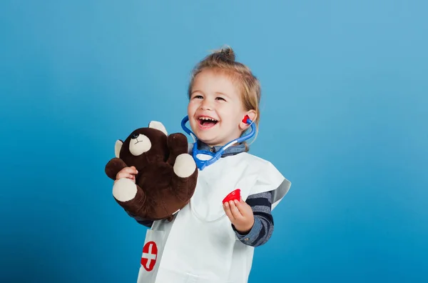 Fröhliches Kindertierarzt-Lächeln mit Teddybär auf blauem Hintergrund — Stockfoto