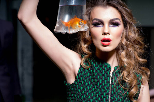 Sensual woman with gold fish in plastic bag