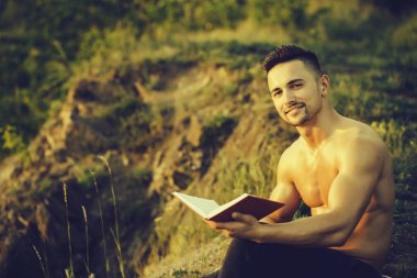 Kitap açık ile gülümseyen kaslı adam