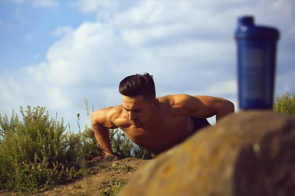 Тренировка мускулистого человека возле бутылки воды — стоковое фото