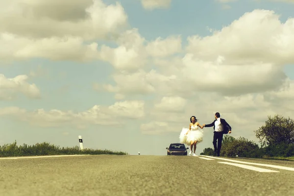 Szczęśliwa para ślub uruchomiona na drodze — Zdjęcie stockowe