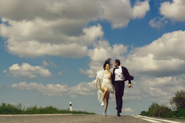 Wedding happy couple running on road — Stock Photo, Image