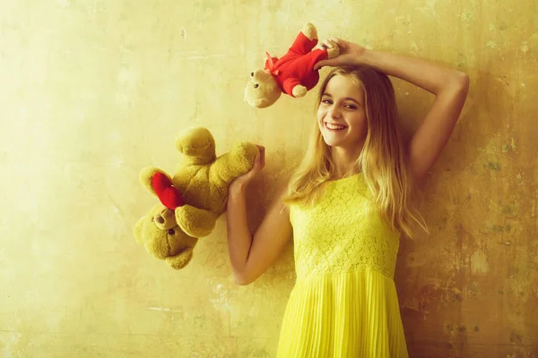 Ziemlich glückliches Mädchen mit Teddybär-Spielzeug im gelben Kleid — Stockfoto