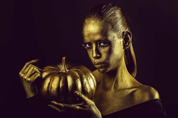 Mulher dourada com abóbora halloween — Fotografia de Stock