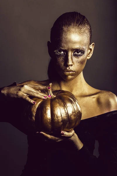 Gouden vrouw met Halloween pompoen — Stockfoto