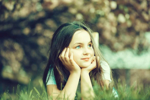 Liten flicka på gräs i blom — Stockfoto