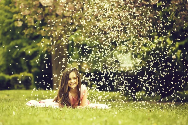 Дівчинка на зеленій траві з пелюстками — стокове фото