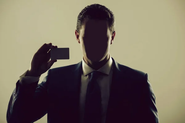 Hombre sin rostro sosteniendo negocio en blanco o tarjeta bancaria — Foto de Stock