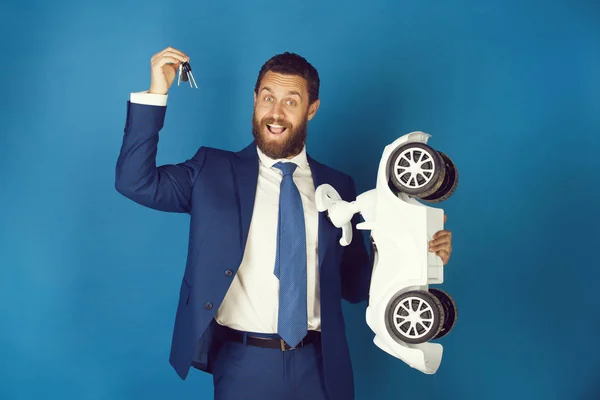Ευτυχισμένος άνθρωπος φορώντας κοστούμι με άσπρο παιχνίδι αυτοκίνητο, πλήκτρα — Φωτογραφία Αρχείου