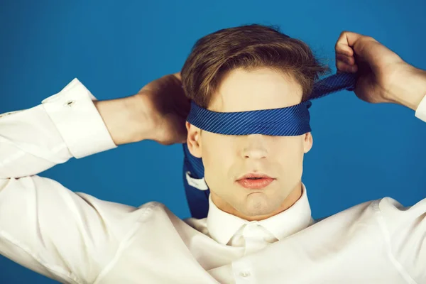 blindfolded man with tie on eyes in white shirt