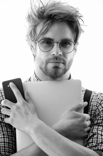 Komea mies silmälaseissa kannettavan tietokoneen ja älypuhelimen kanssa — kuvapankkivalokuva