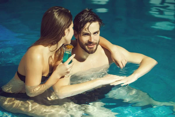 Gespierde man en sexy vrouw in blauwe zwembad met cocktail — Stockfoto