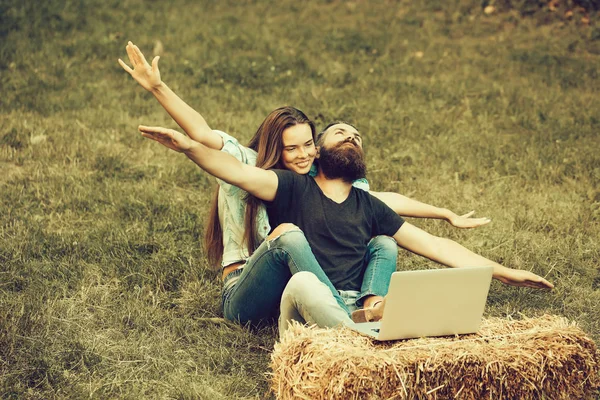 Happy couple in love with flying gesture and laptop outdoor — Stock Photo, Image
