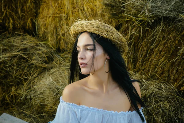 Woman with long brunette hair on dried grass, farm