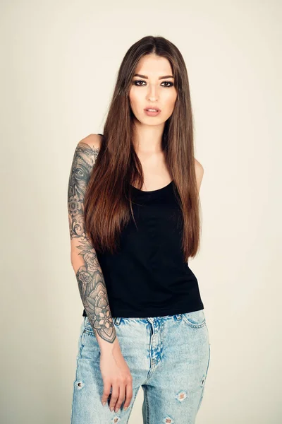 Woman with tattoo arm in jeans, fashion. — Stock Photo, Image
