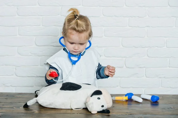 Boy play doctor with toy cow on white wall