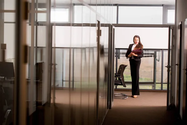 Woman in formal outfit in glass office.