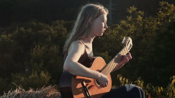 女孩弹吉他 妇女在日落演奏吉他 — 图库视频影像