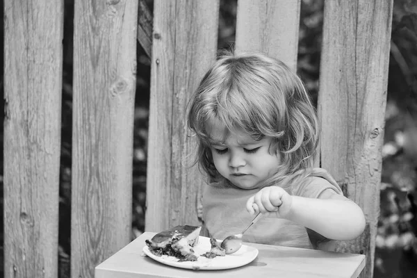 Kleine jongen eten taart in de buurt van houten hek — Stockfoto