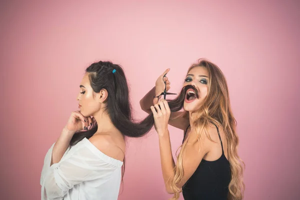 Mulheres com tesoura cortar o cabelo no fundo rosa . — Fotografia de Stock