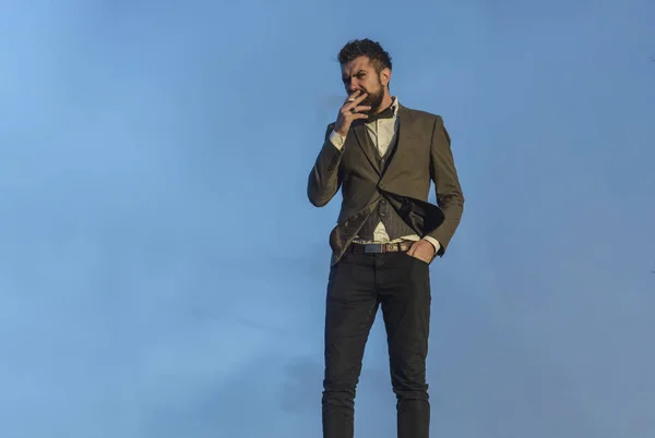 Hombre con barba y cigarrillo con cielo dramático en el fondo . — Foto de Stock