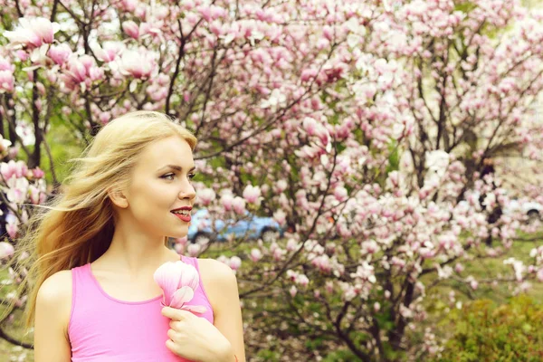 Jonge mooie vrouw in de buurt van magnoliaboom met bloemen — Stockfoto