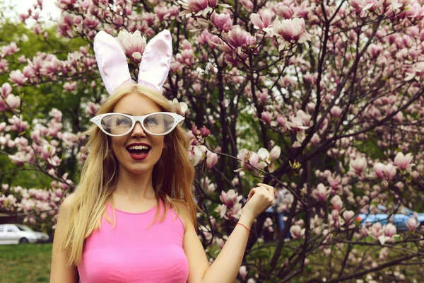 Chica feliz riendo de árbol en flor con flores de magnolia — Foto de Stock