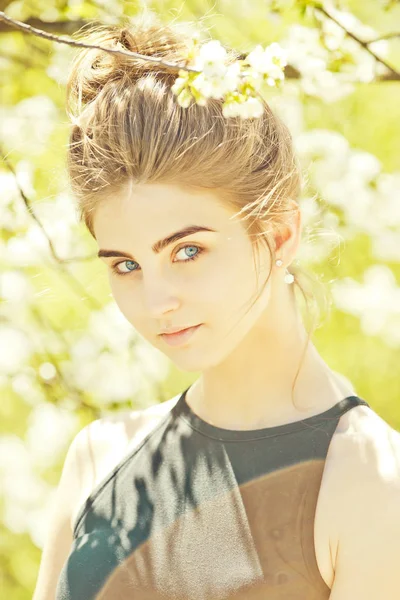 Ładna kobieta o niebieskich oczach pozowanie wśród białych, kwitnących kW — Zdjęcie stockowe