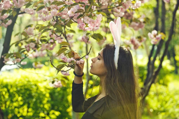 さくらの花の臭いがする楽観的なウサギの耳とかわいい女の子 — ストック写真