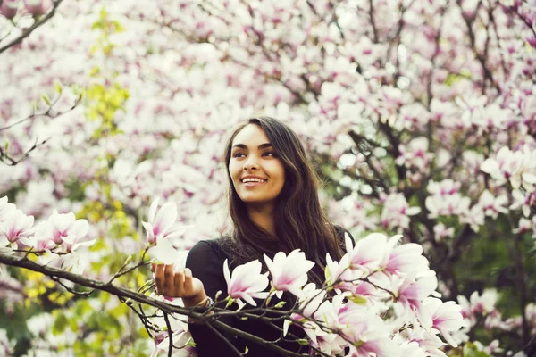 Mulher feliz sorrindo para a magnólia árvore com flores florescentes — Fotografia de Stock