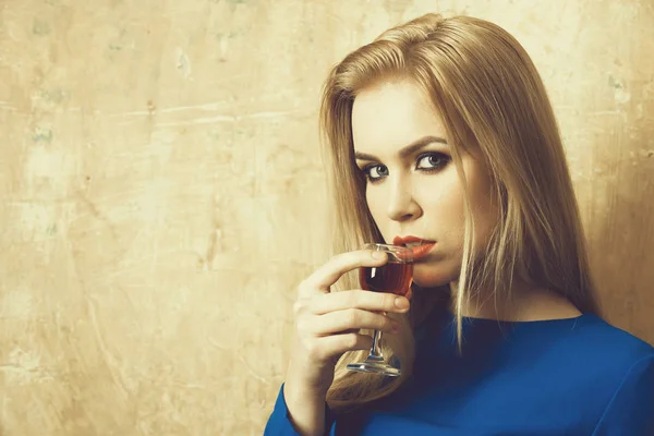 Mujer bebiendo licor rojo en vaso — Foto de Stock
