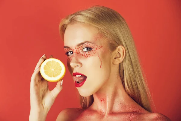 Hübsche blonde Frau mit kreativem modischem Make-up lecken Zitrone, — Stockfoto