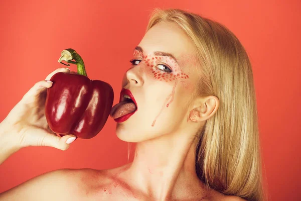 Vrouw met creatieve modieuze make-up likken paprika — Stockfoto