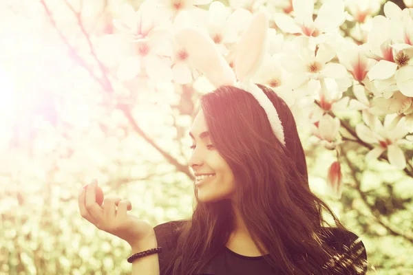 Vrouw die lacht met schattige bunny oren op Magnoliaboom — Stockfoto