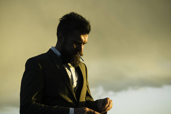 Человек с бородой и сигаретой на фоне яркого неба
.