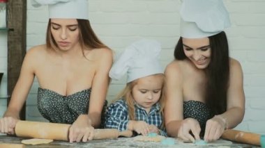 Lezbiyen çift ile onların evlat edinilmiş çocuk yemek. Kız onların kardeşi ile pişirme.