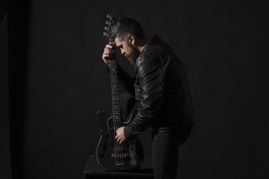 Gri arka plan üzerinde sakallı adam gitar tutar