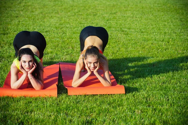 Idrott kvinnor utbildning på yogamattor på grönt gräs — Stockfoto