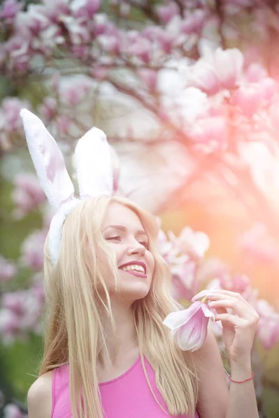 Pasen, grappige vrouw in glazen en bunny oren op voorjaar magnolia bloem. — Stockfoto