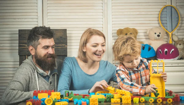 Eltern mit glücklichen Gesichtern und Kind bastelt Ziegelsteine. — Stockfoto